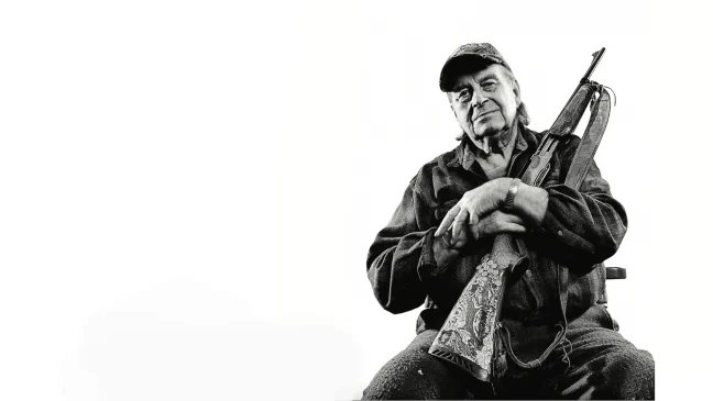 Legendary deer hunter Larry Benoit holding his Remington 7600 rifle on white background.