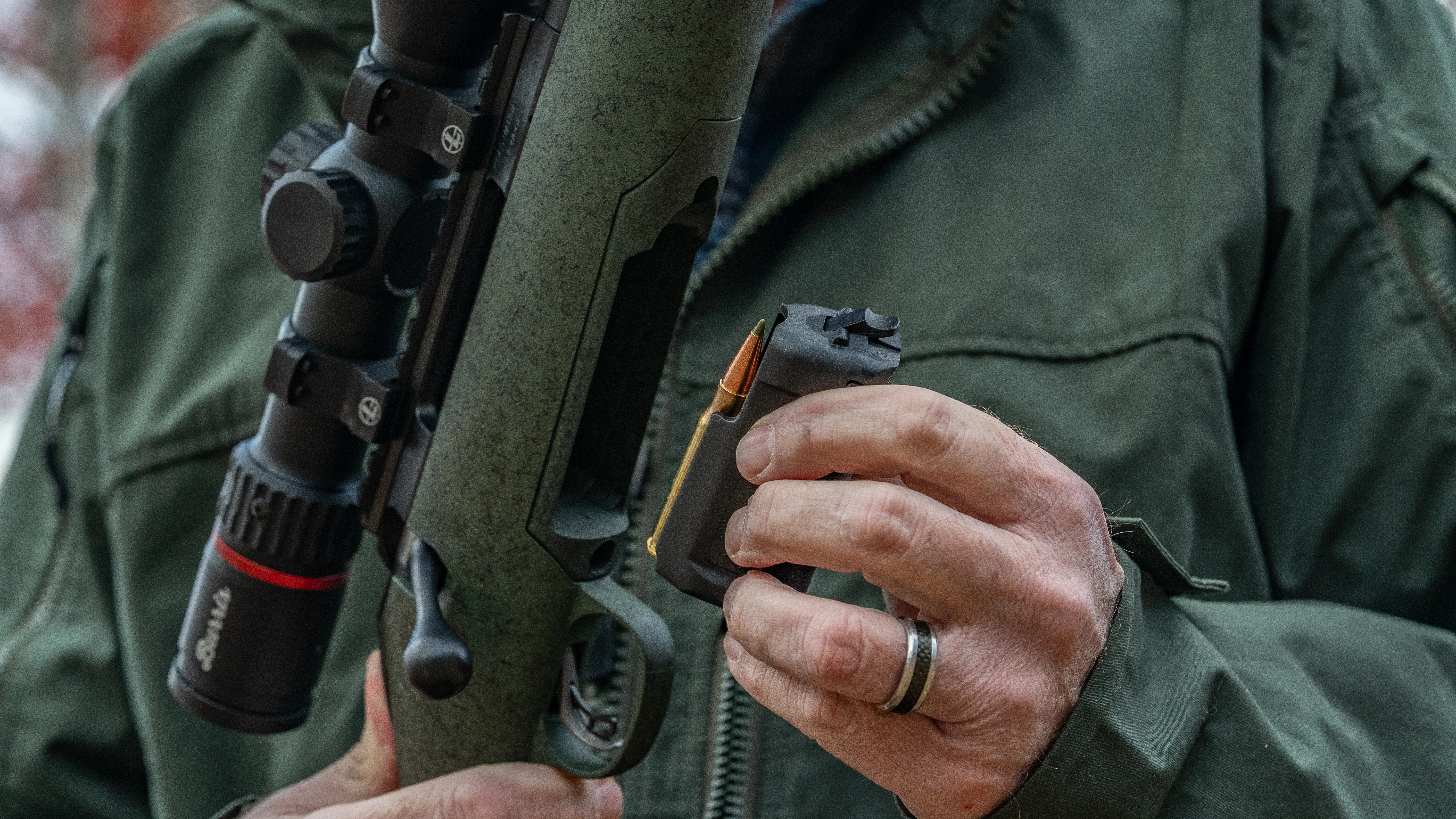 A shooter loads the detachable magazine in a rifle.