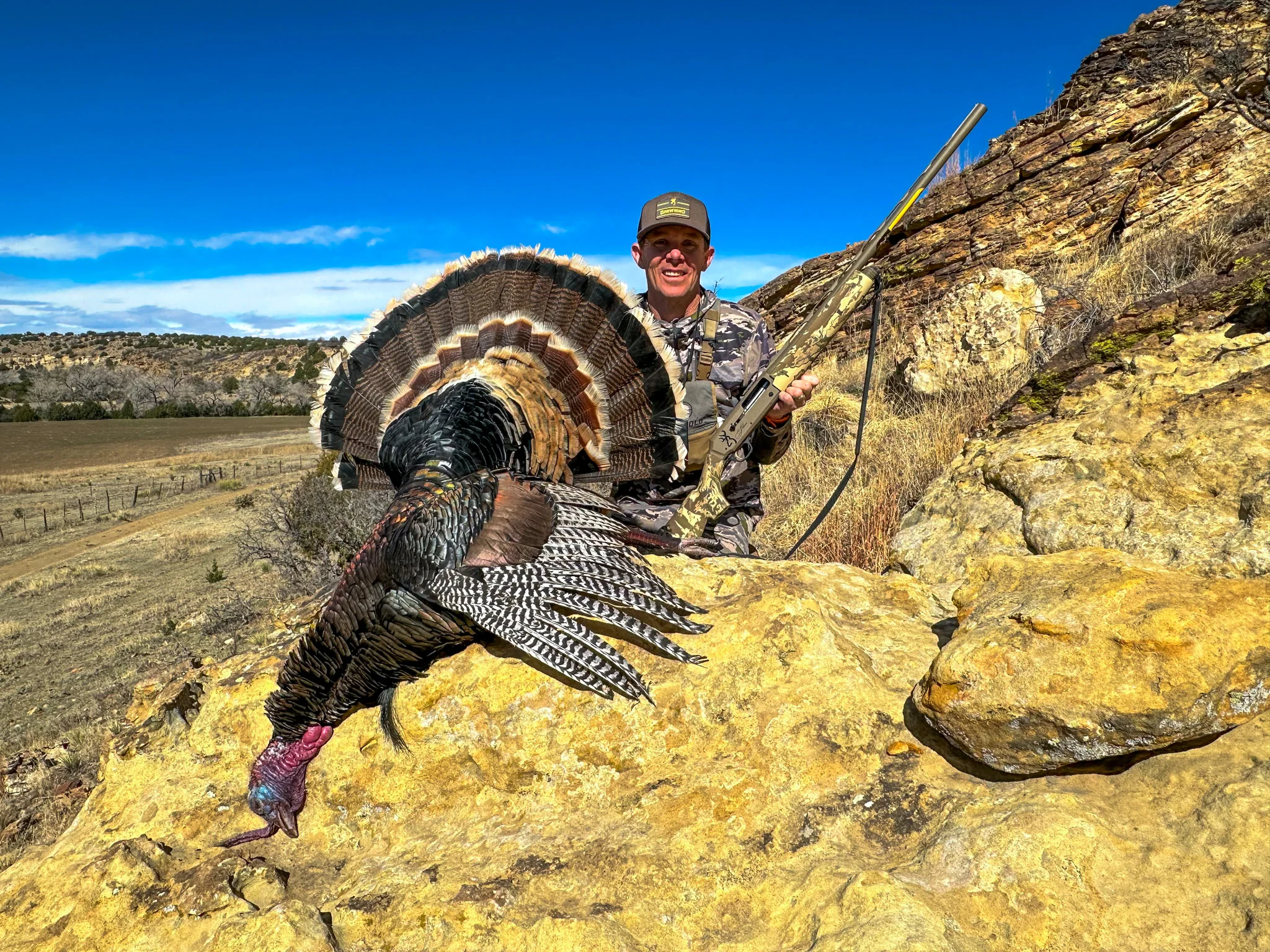 Hunter posing with a turkey on a rock