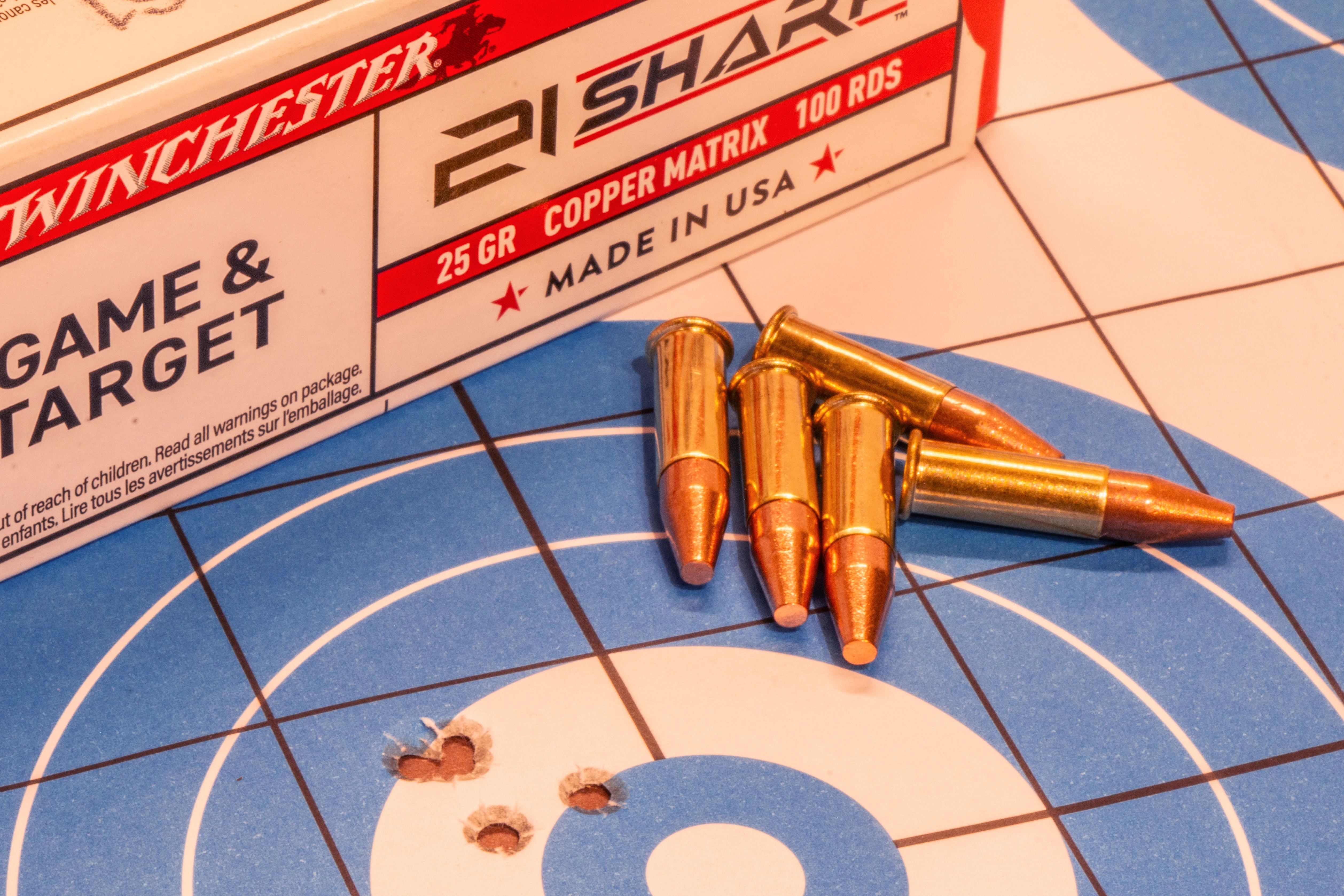 Winchester's new 21 Sharp cartridges lying on a target with bullet holes.