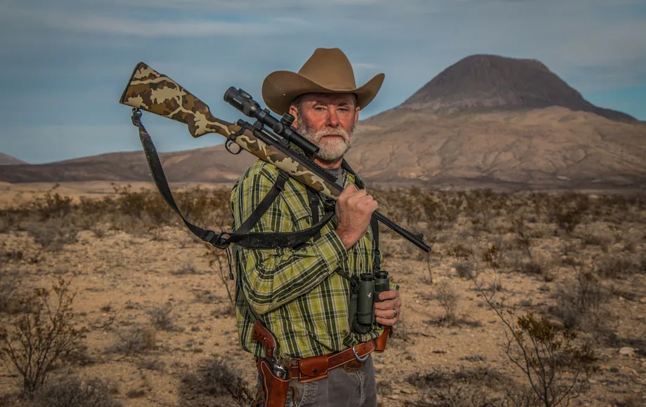 Man holding a great hunting rifle in a desert