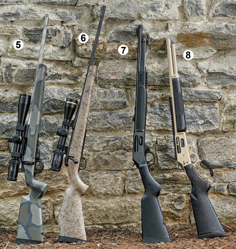 Four rifles leaning against a stone wall.