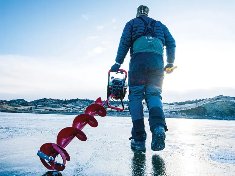 man carrying ice drill