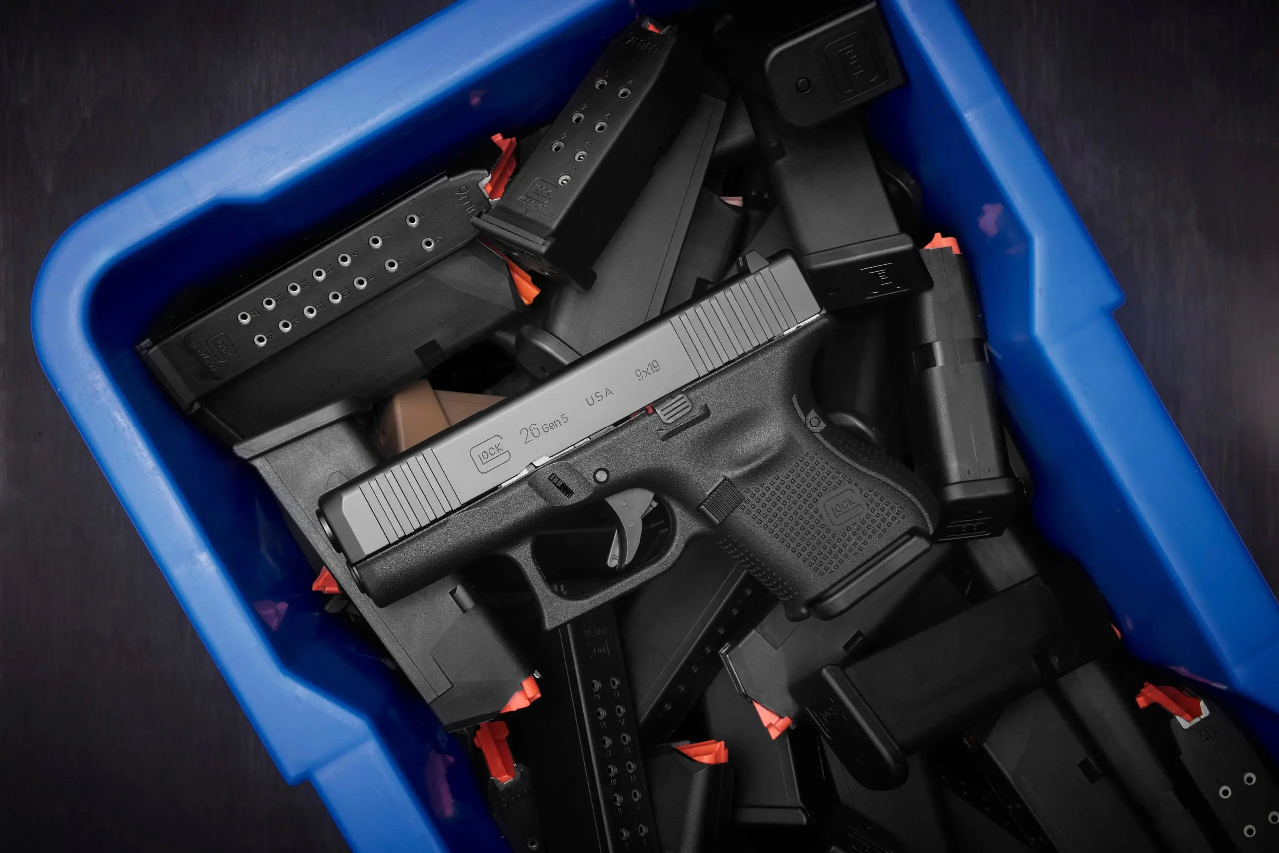 Glock 26 Gen 5 pistol in a blue bin with assorted magazines