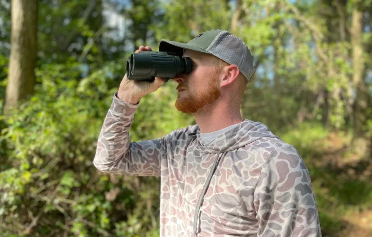 Man looking through Vortex Fury Rangefinder Binoculars in the woods