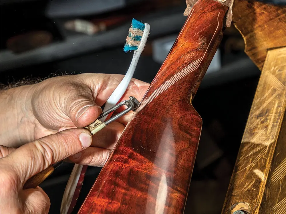 a wood worker carving a pattern into a rifle stock