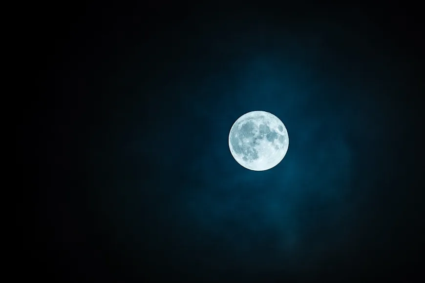 A full moon in the night sky with no stars.