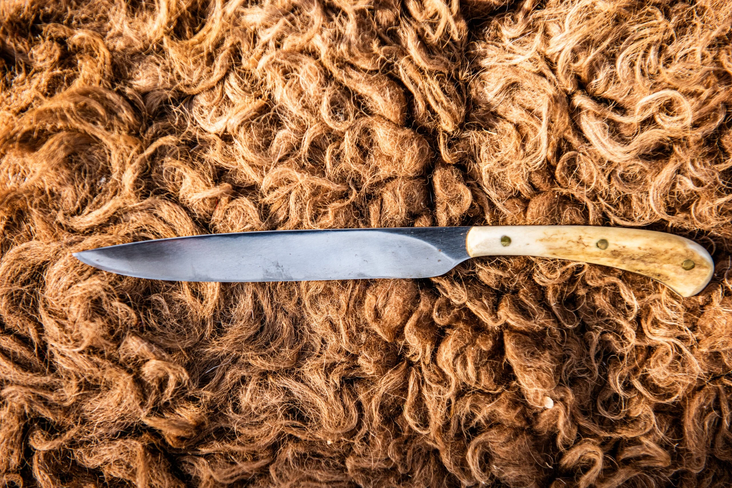 Handmade belt knife with stag handle lying on a buffalo hide