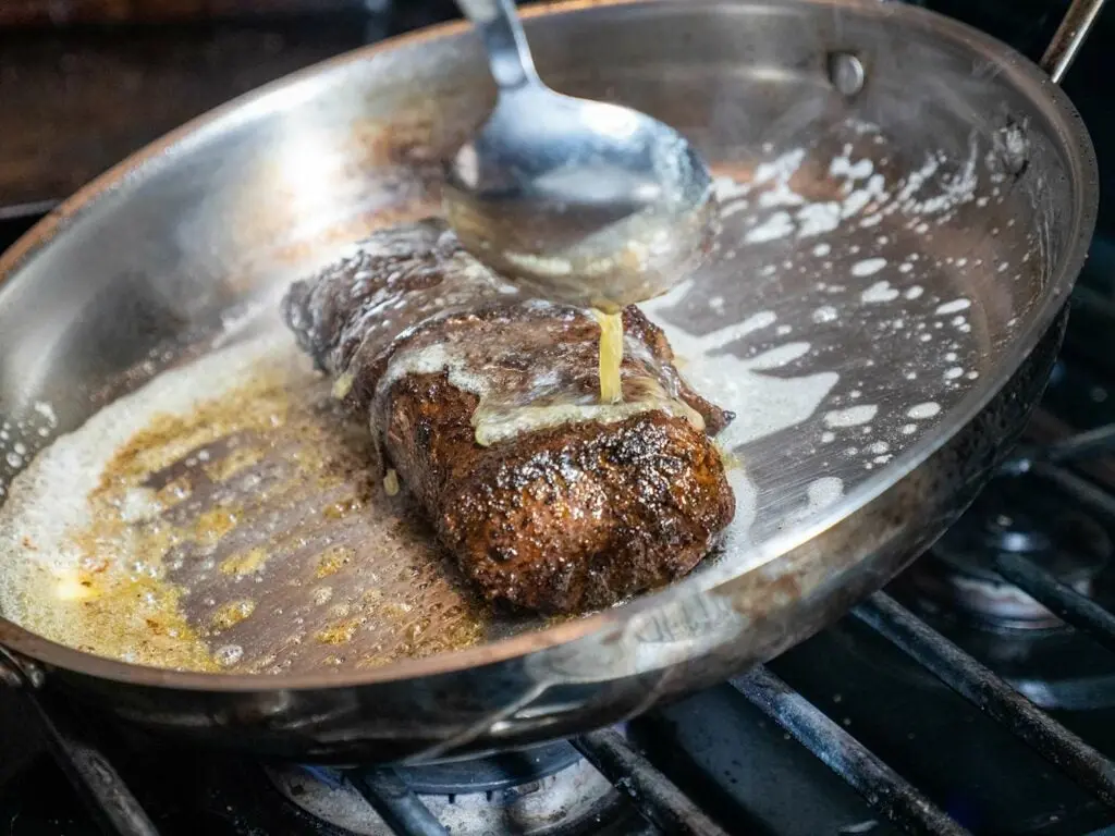 Basting a venison backstrap in a pan.