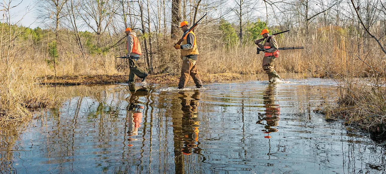 three hunters walking through swamp