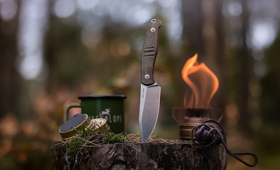 The new Giant Mouse GMF2 Scout knife with the point stuck into a stump in a camp scene.