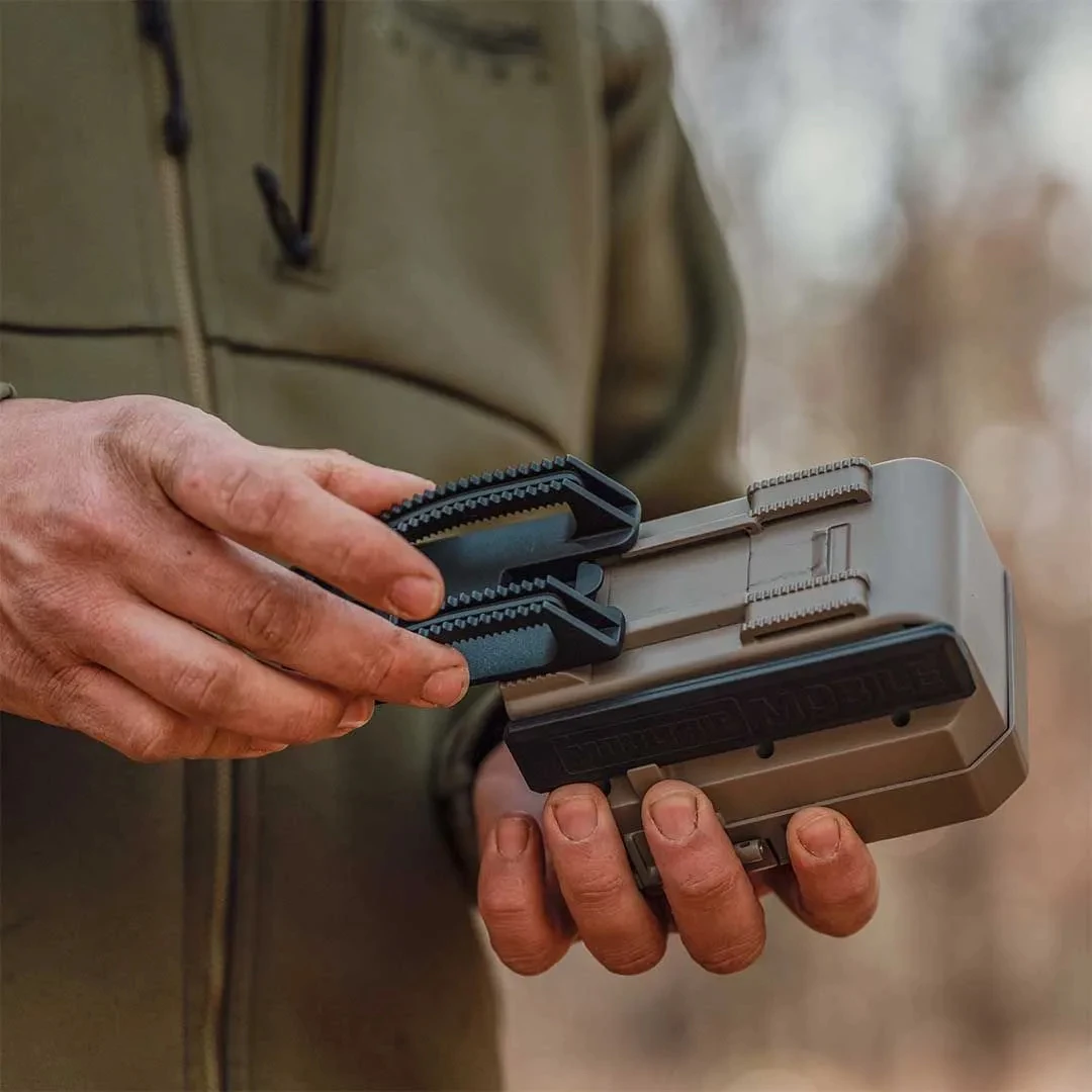 A man attached an Easy-Aim-Mount bracket to a Moultrie Mobile Edge Pro 2 trail camera.