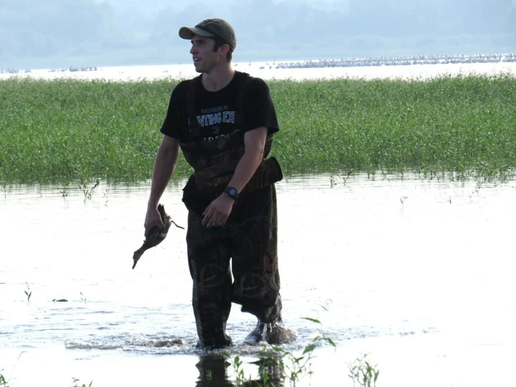 Hunter with duck in his hand standing in the water