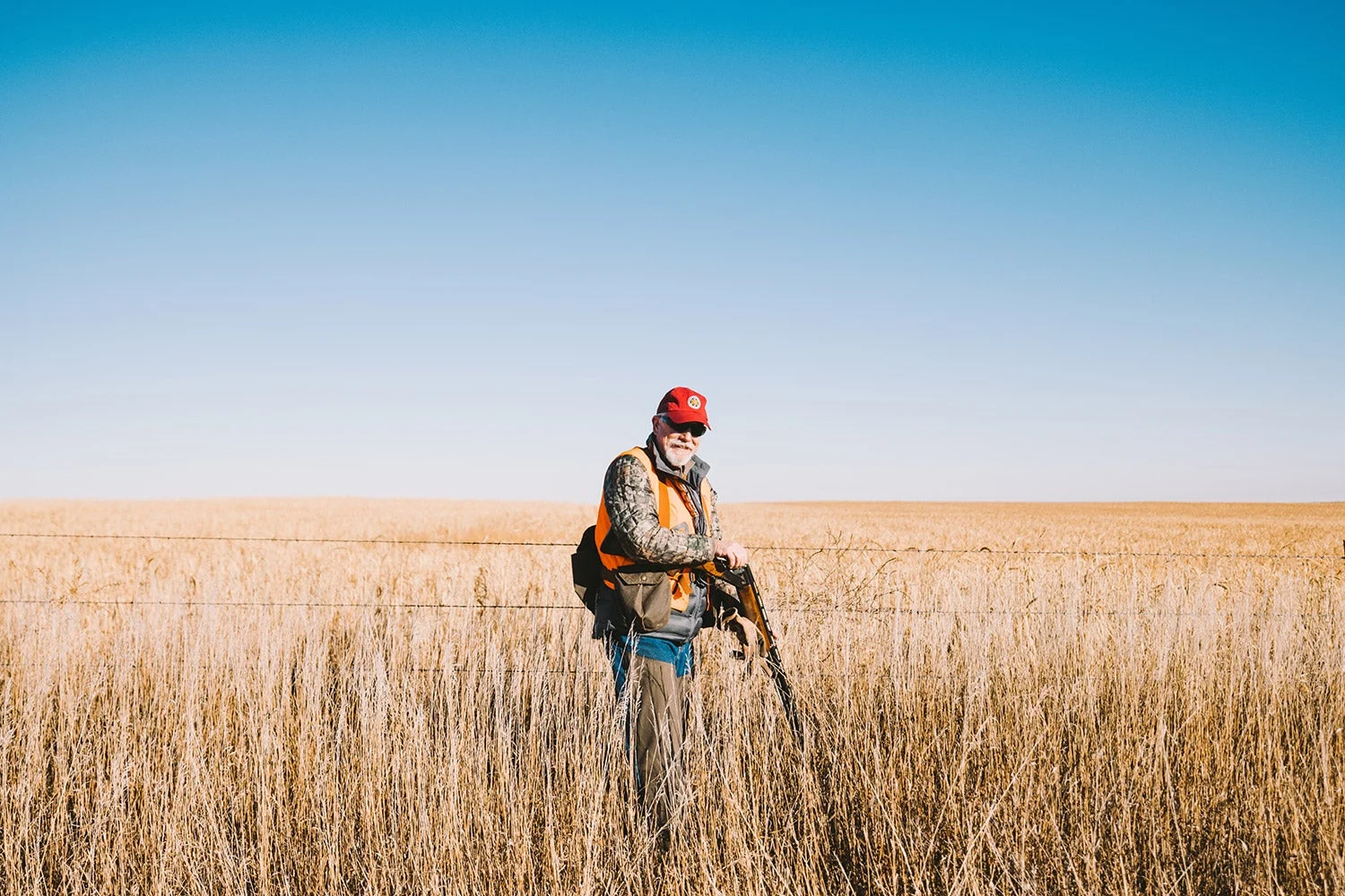 bird hunter reloads shotgun near barbed-wire fence