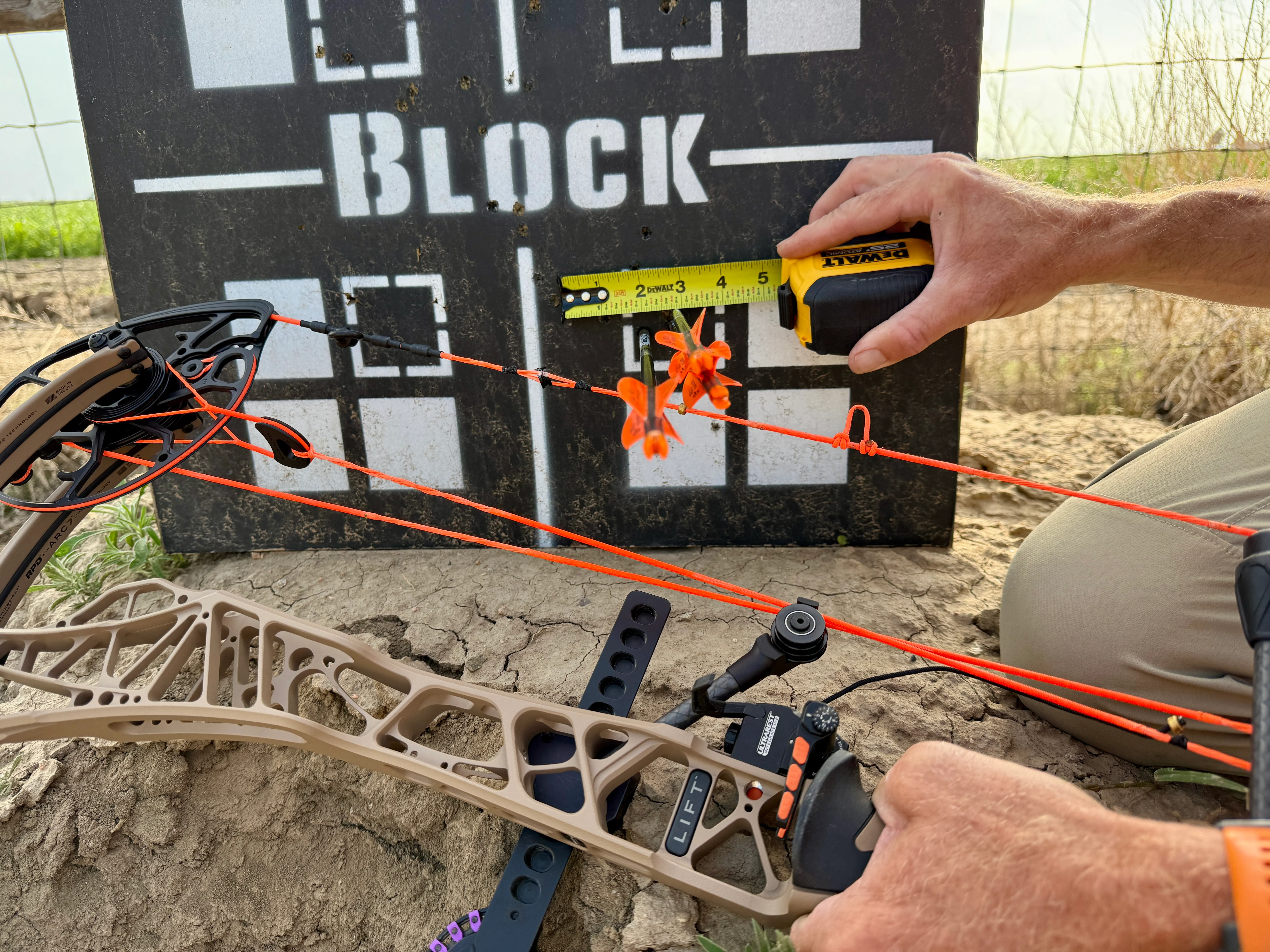 Photo of an archer measuring a group of arrow shot into a target. 