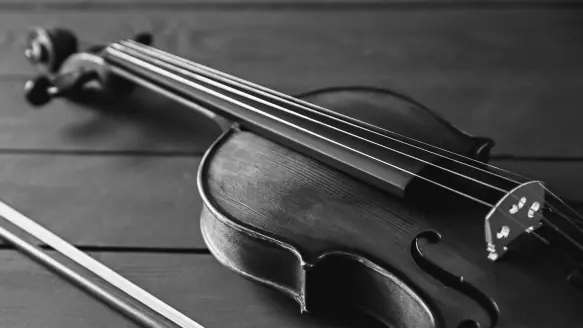 A fiddle and bow lay on a wooden table