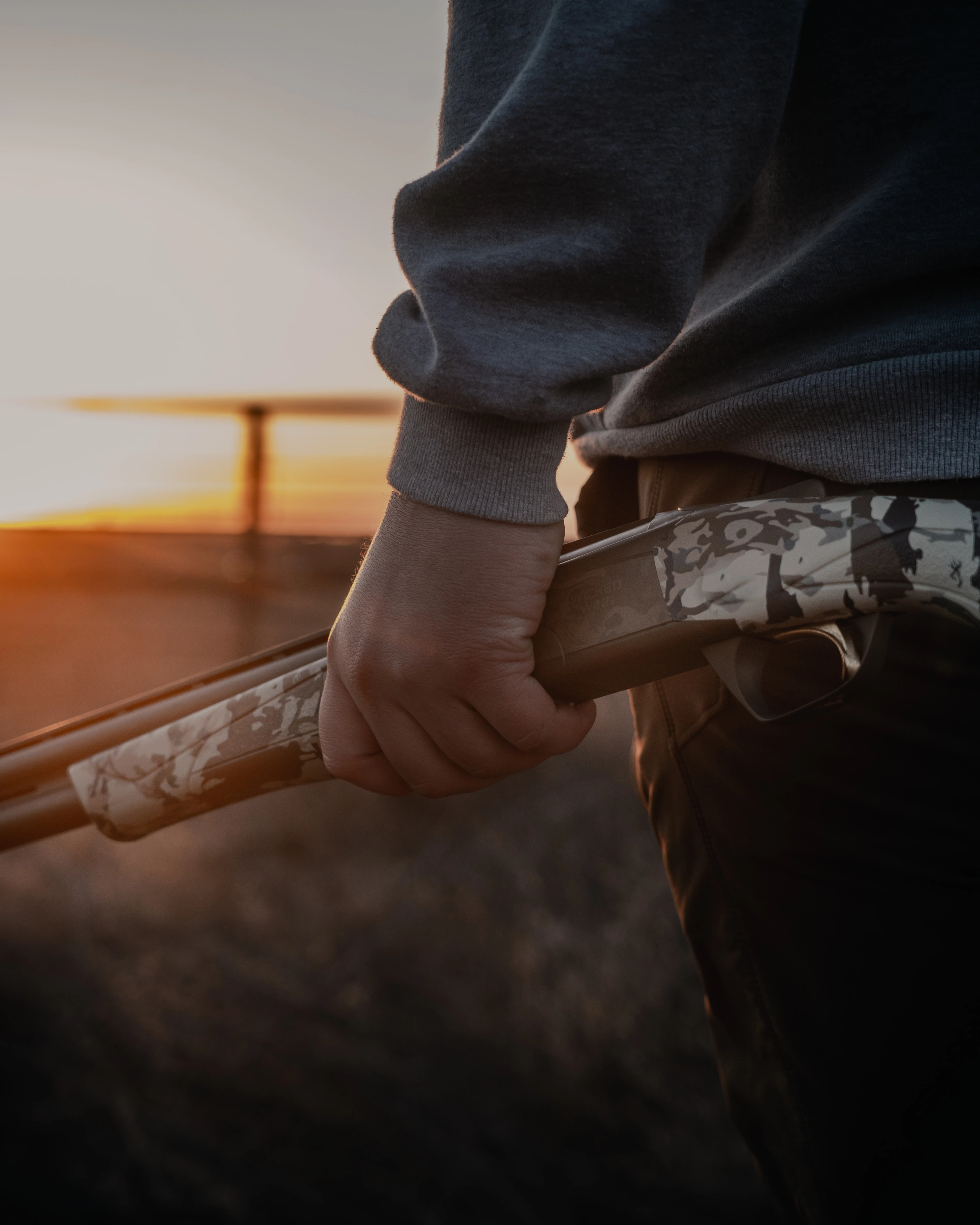 A hunter holds a Browning Cynergy over-under shotgun as he walks in a field. 