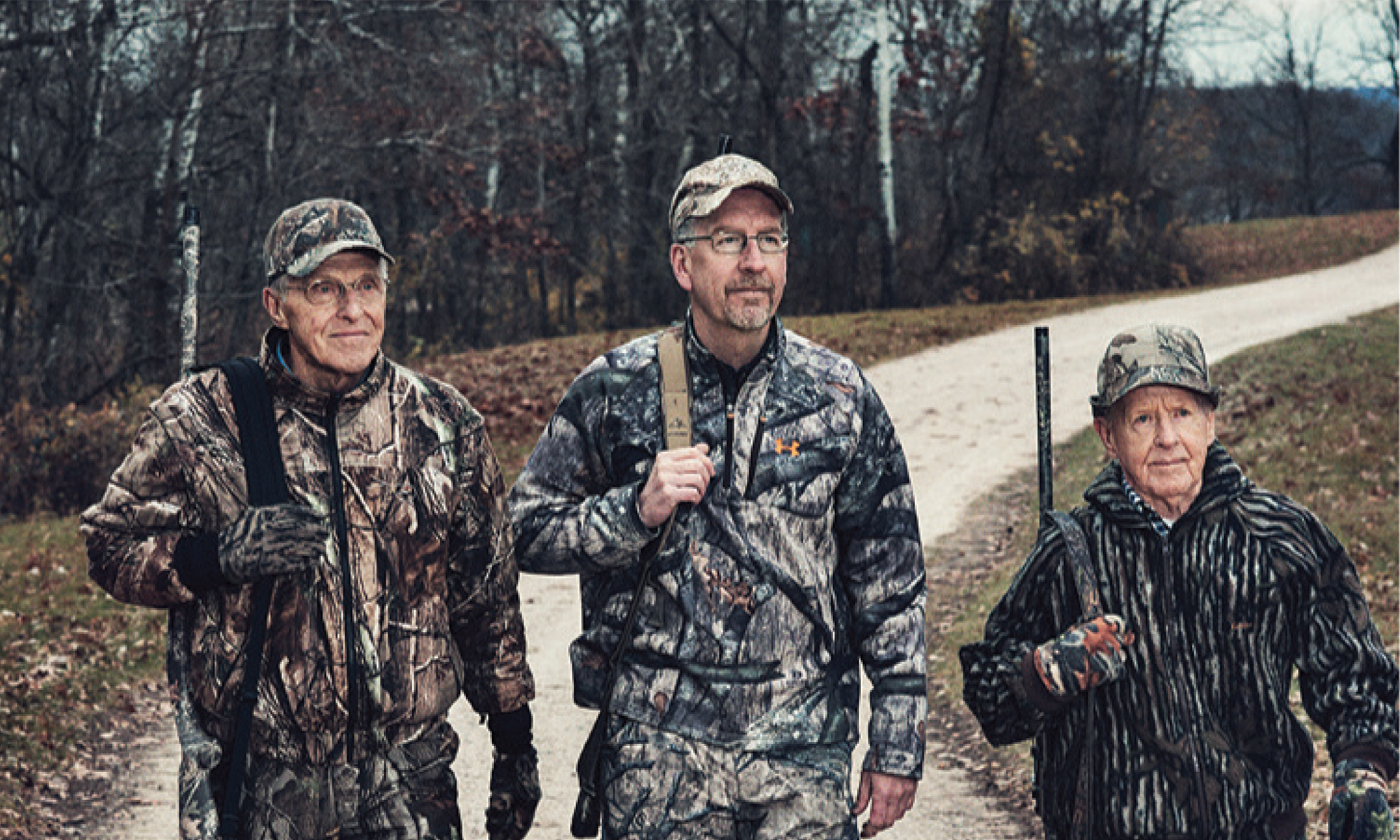 Three turkey hunters walk down a road. 