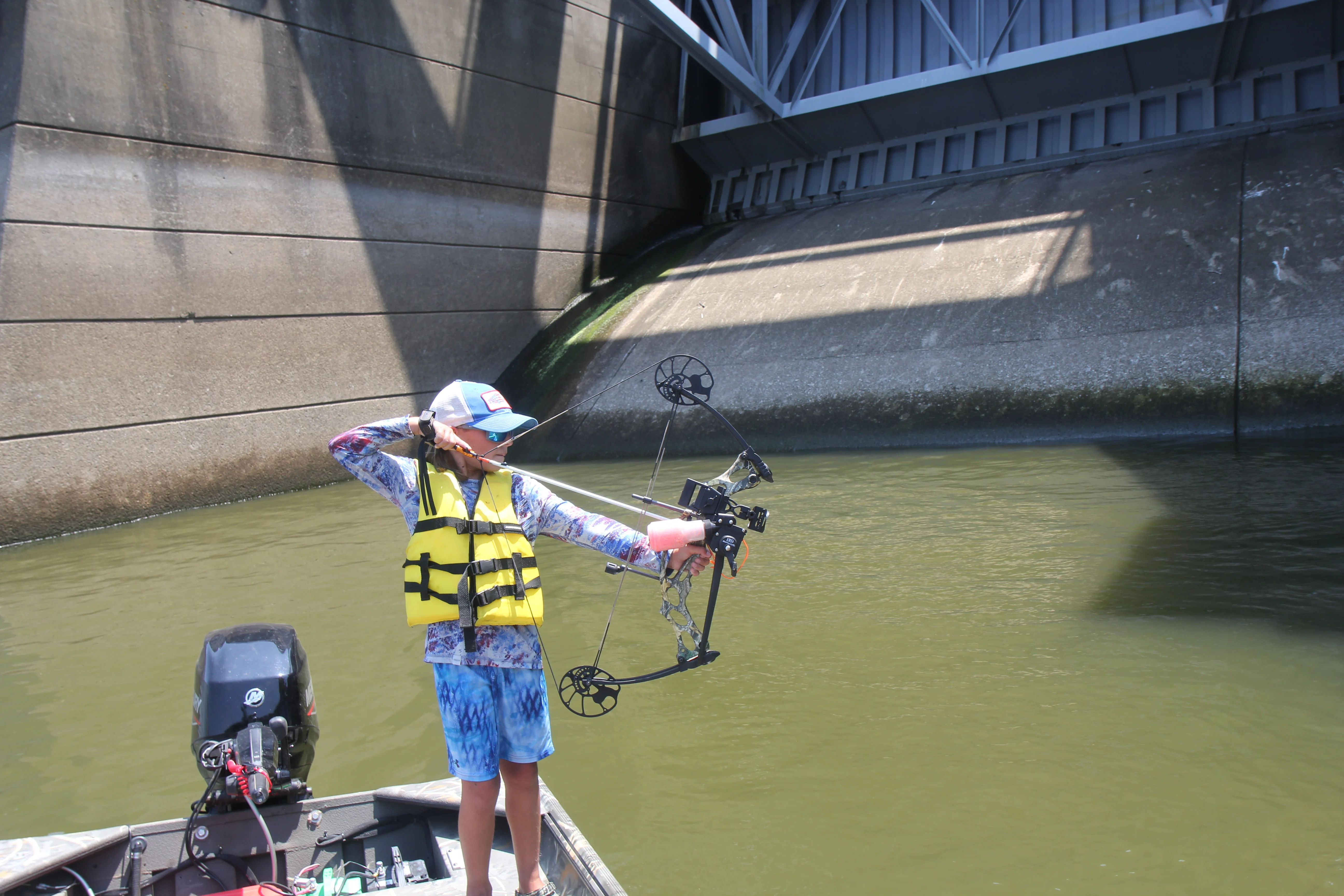 Bowfisherman at full draw on boat