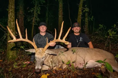 Two hunters pose with a wide-racked trophy whitetail taken with a bow in Missouri. 