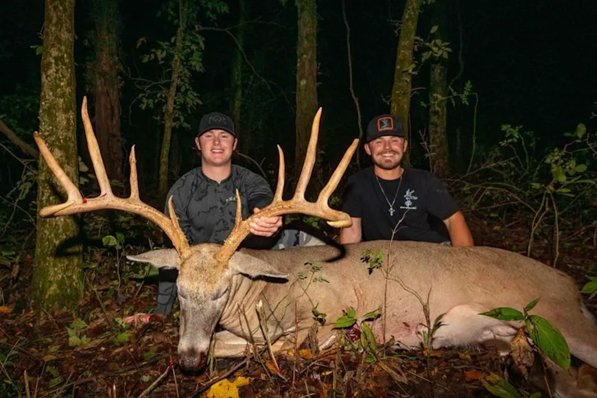 Two hunters pose with a wide-racked trophy whitetail taken with a bow in Missouri.