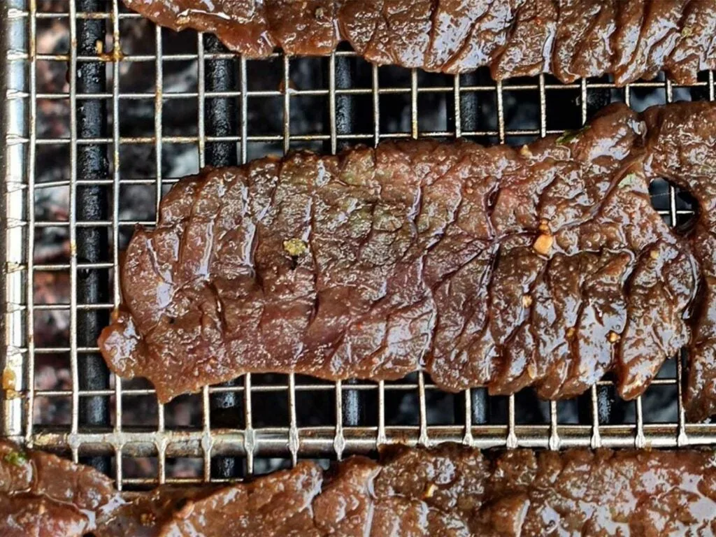 Cooked beef jerky on a wire rack.