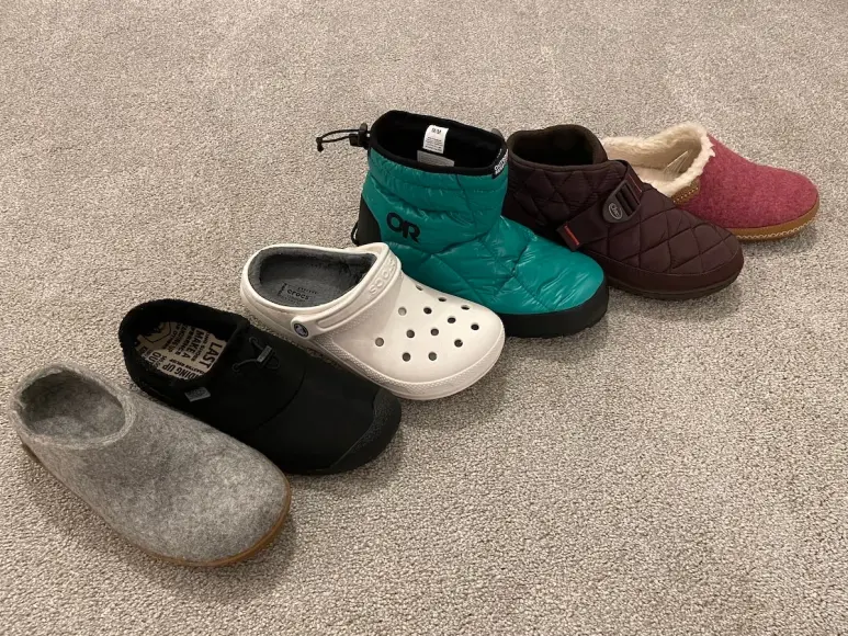 Six pairs of indoor outdoor slippers lined up on carpet