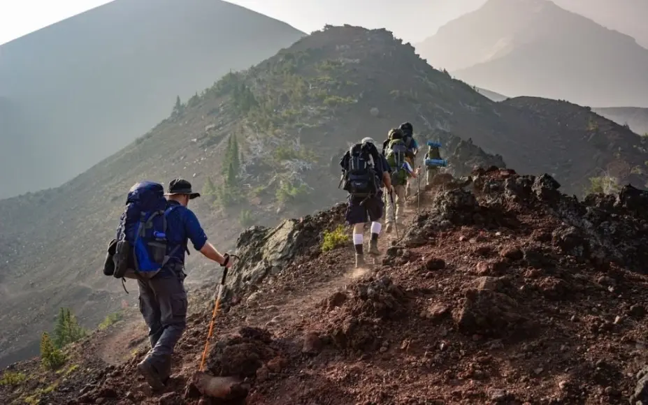 Group of people walking and hiking into the mountains with backpacks in their shoulders.