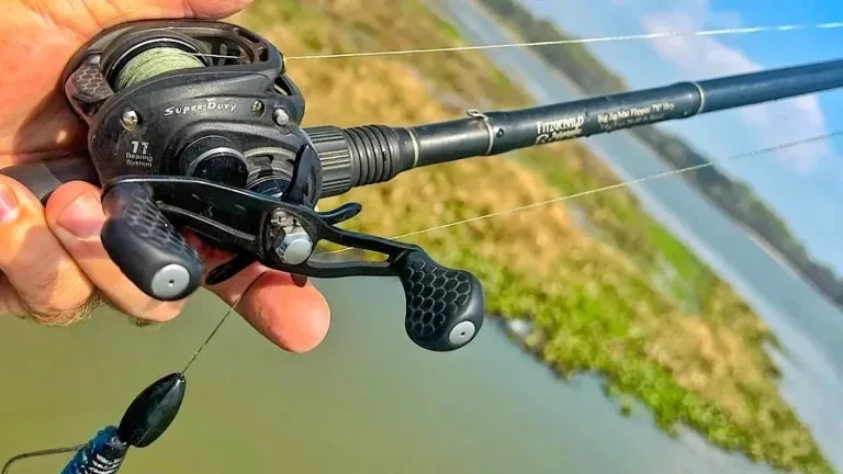 An angler holds a baitcasting rod and reel, ready to make a cast.