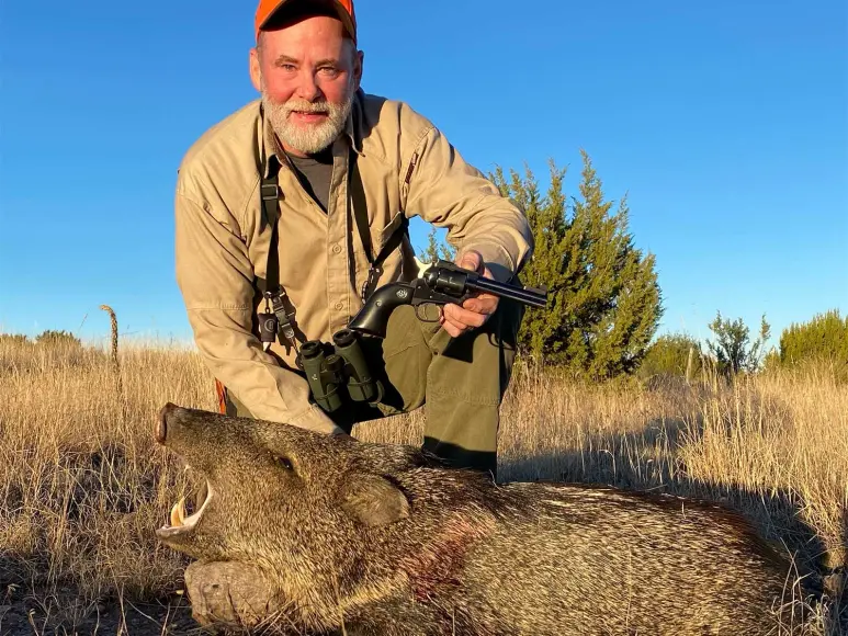 Hunter kneeling behind a wild pig.