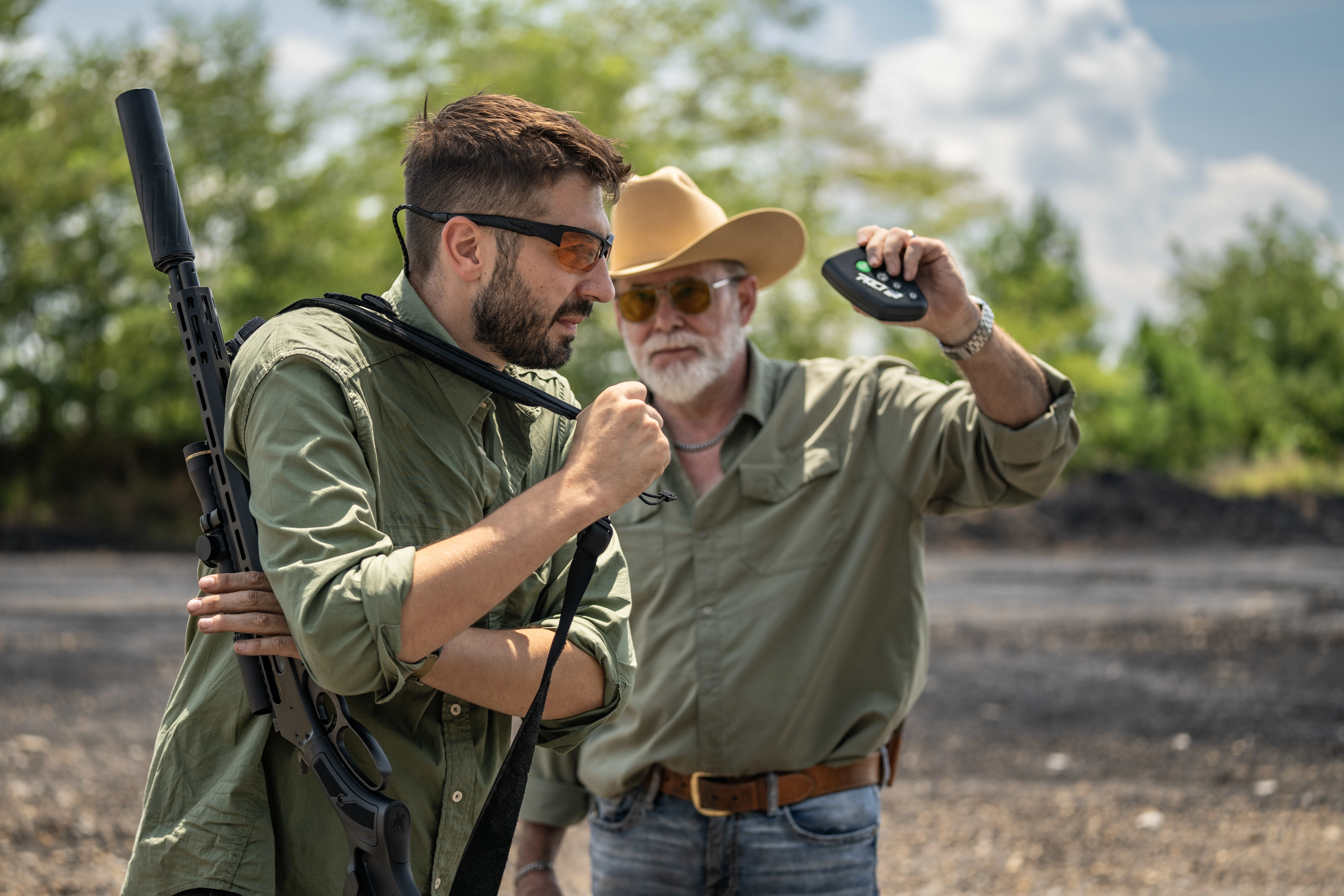 A shooter in a green shirt with a rifle slung on his shoulder