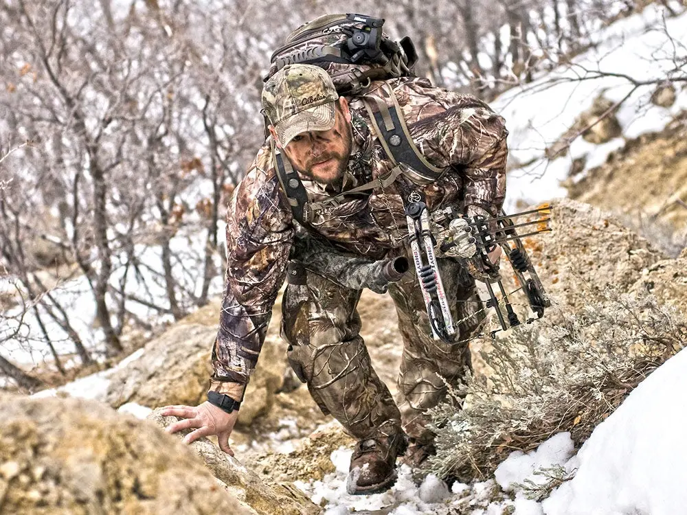 hunter sneaking through snow and grass