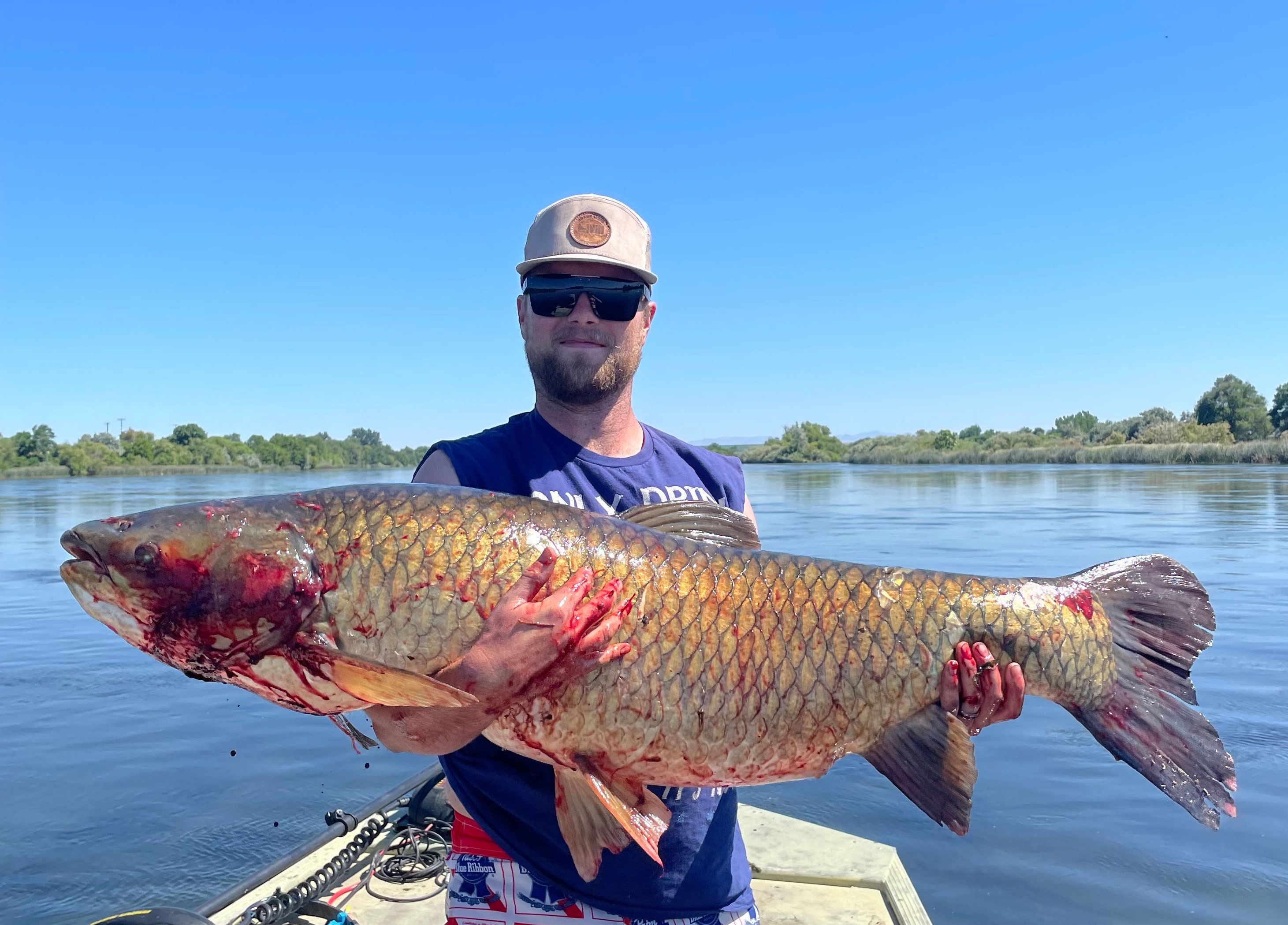 A bow fisherman poses with a record-breaking grass carp. 