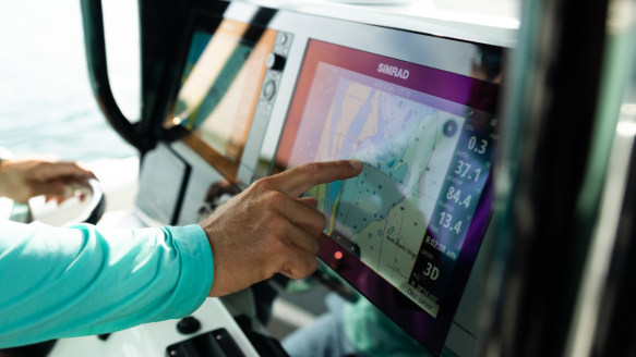 Man using Simrad fish finder on boat