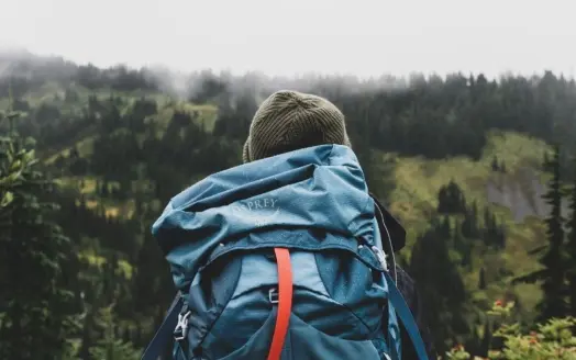 Person holding a blue internal frame backpack