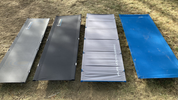 Four portable camping cots set up on grass