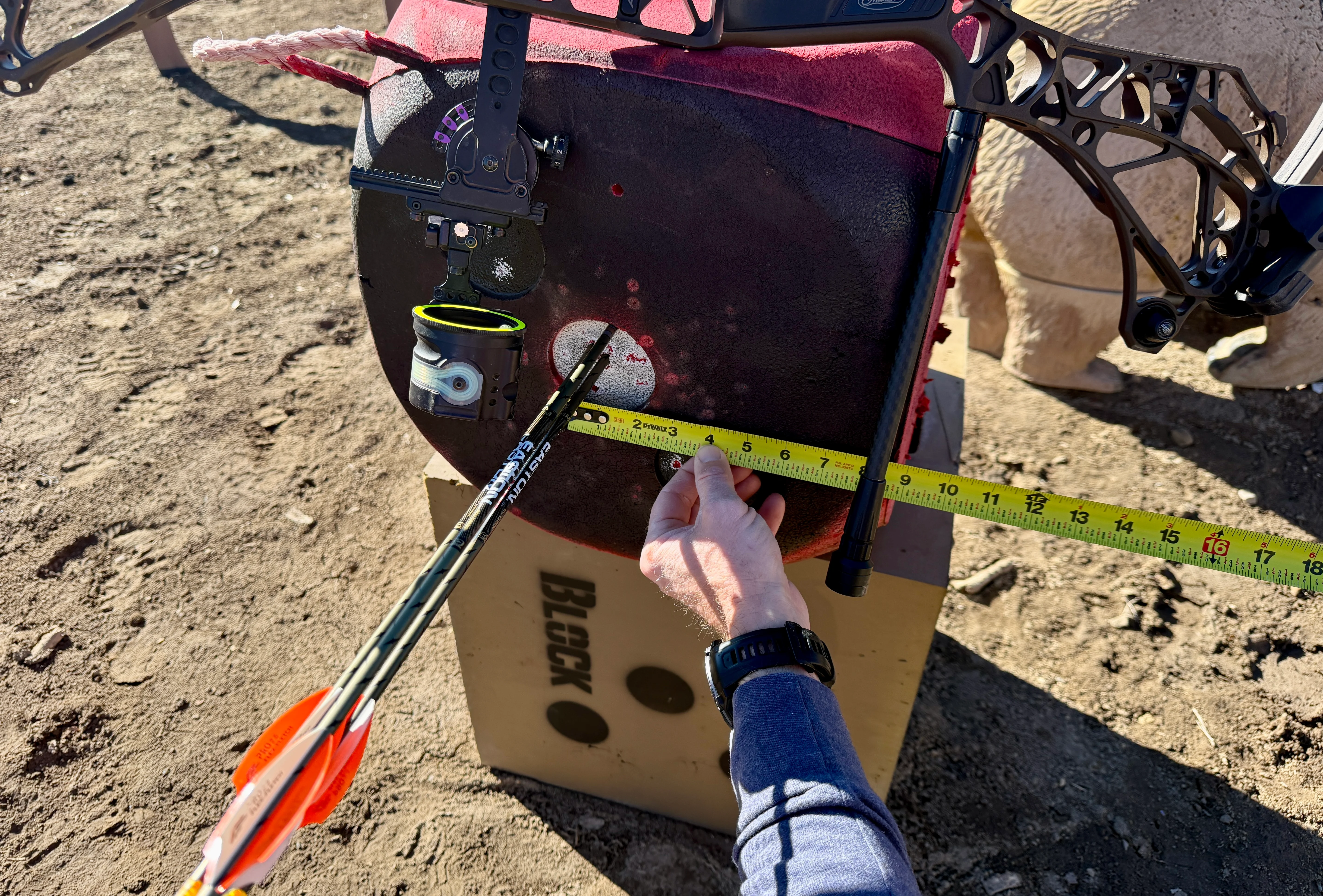 A bowhunter measures a very small group of arrow in a block target. 