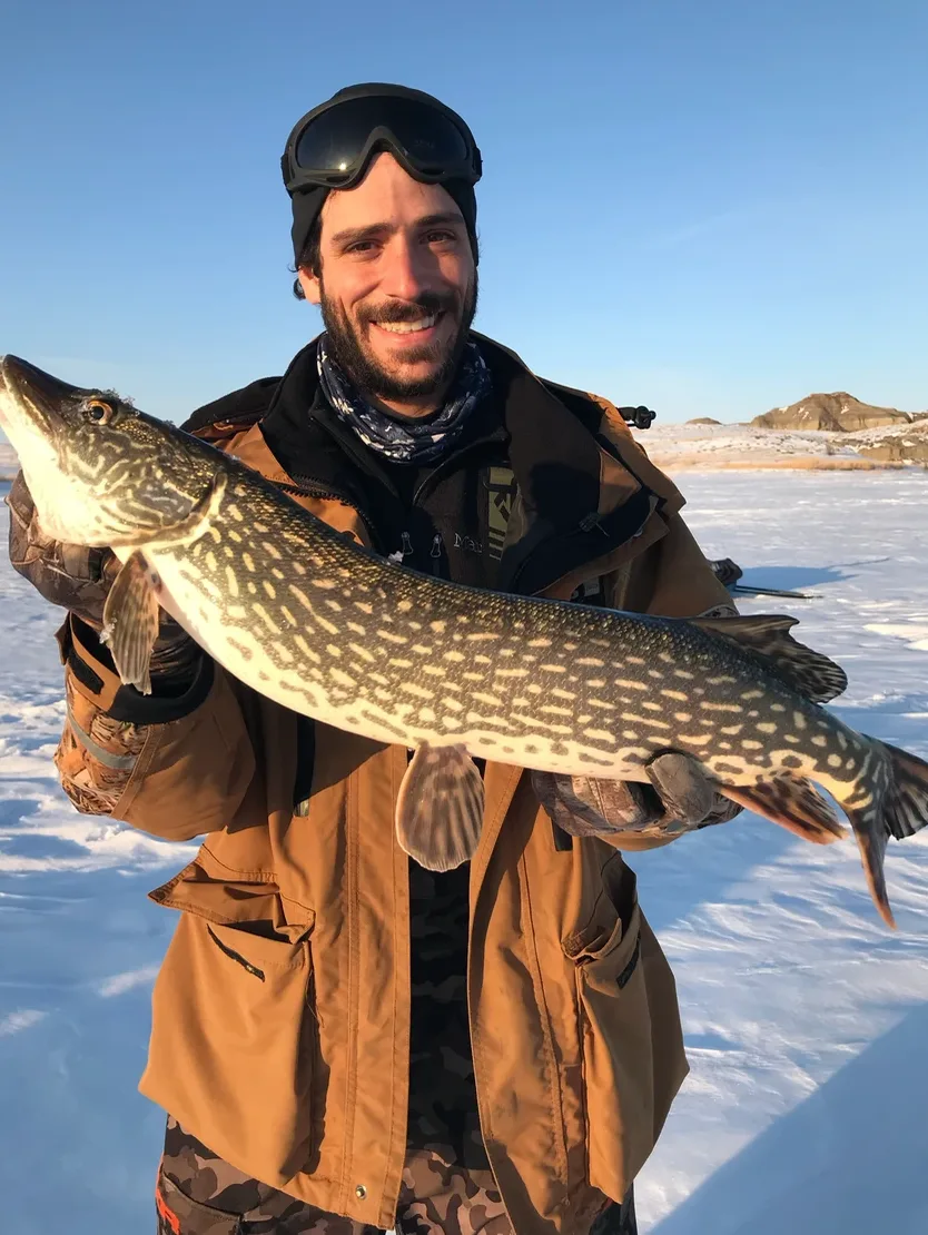 An angler poses with a pike caught while ice fishing in Montana. 