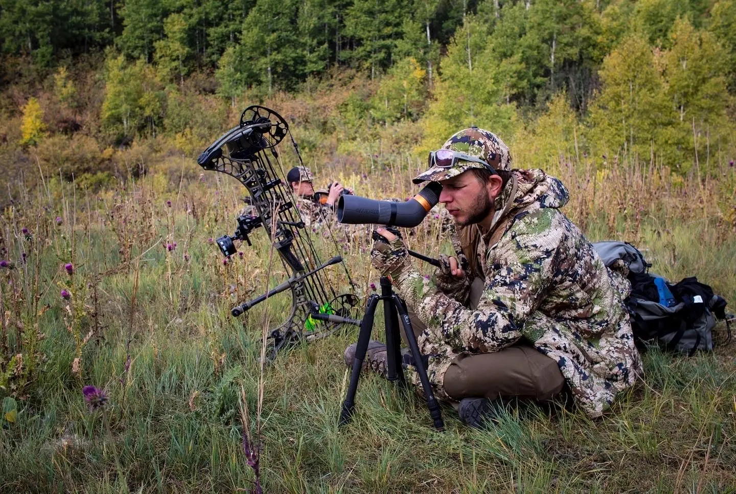 Hunter looking through maven CS.1A spotting scope with bow in the background