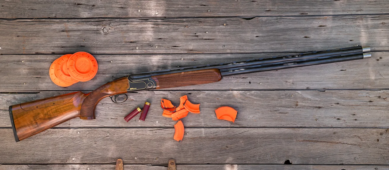 Rizzini BR240 Cole Special Sporting shotgun on a wood surface with clay targets.