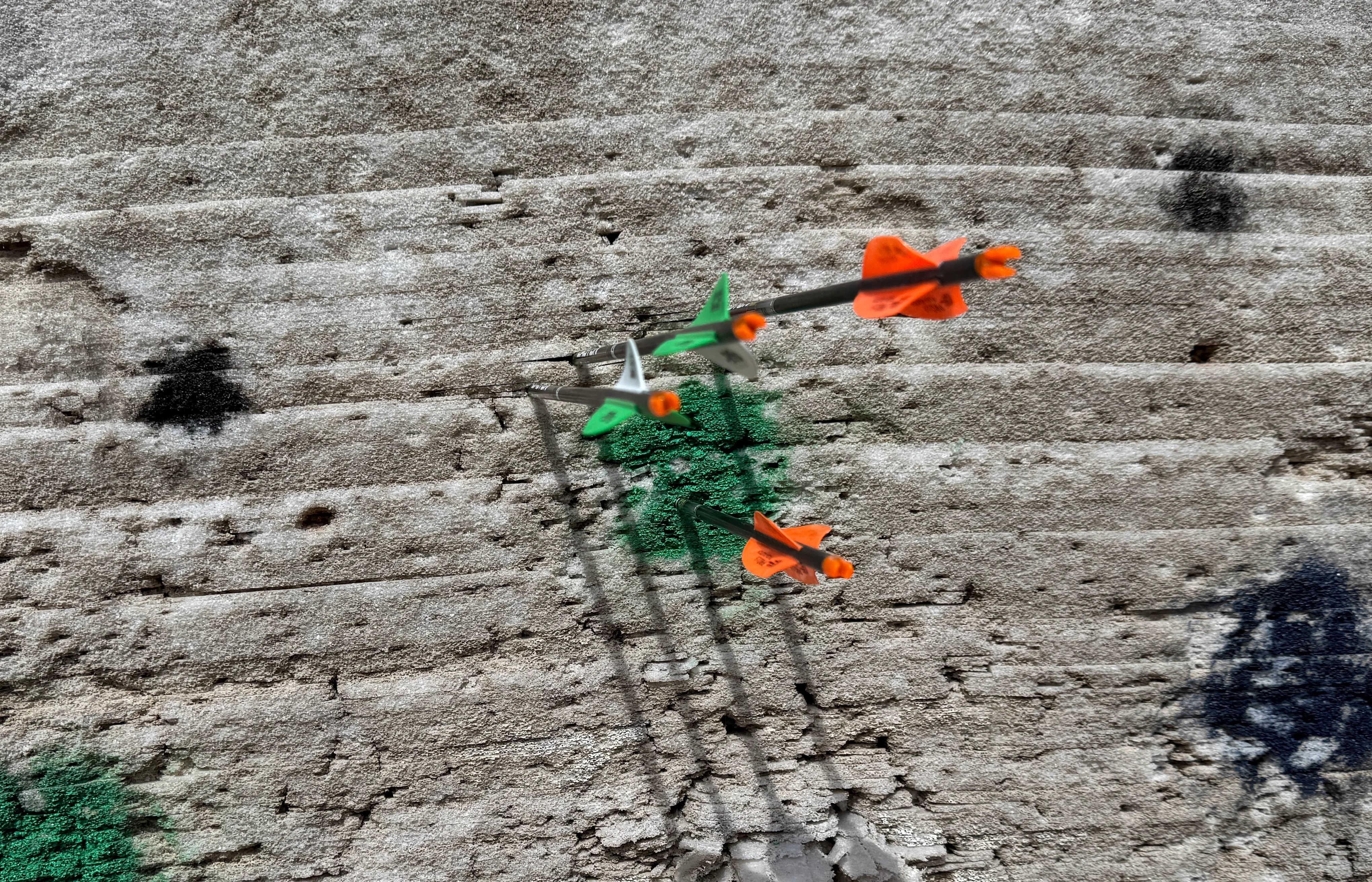 Two three-fletch arrows and two four-fletch arrows stuck in a target 