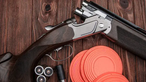 Photo of a shotgun, a shell, and clay birds