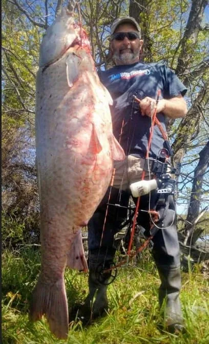 A bow fisherman poses with a world record smallmouth buffalo.
