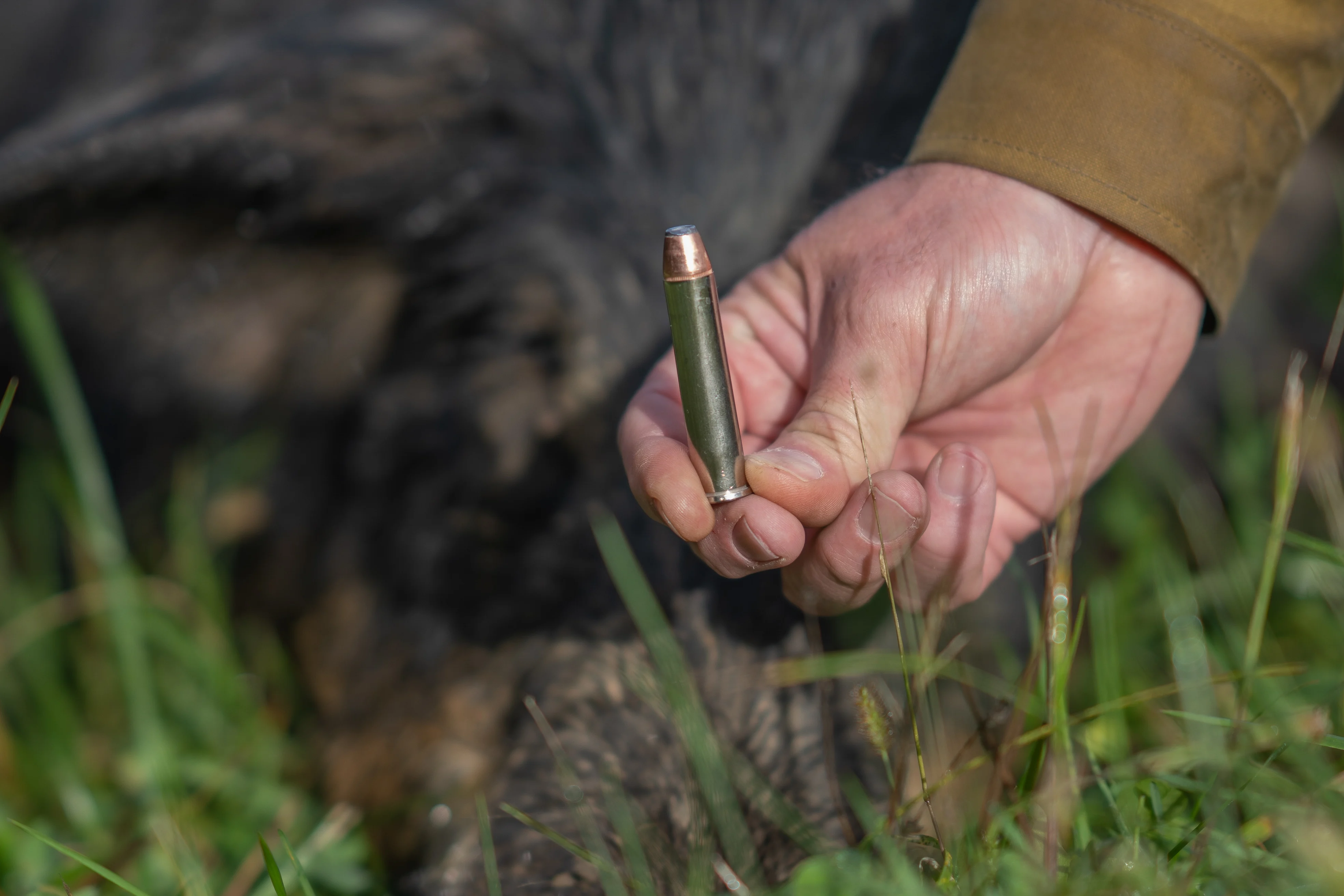 A hunter holding up a 45-70 cartridge in one hand.
