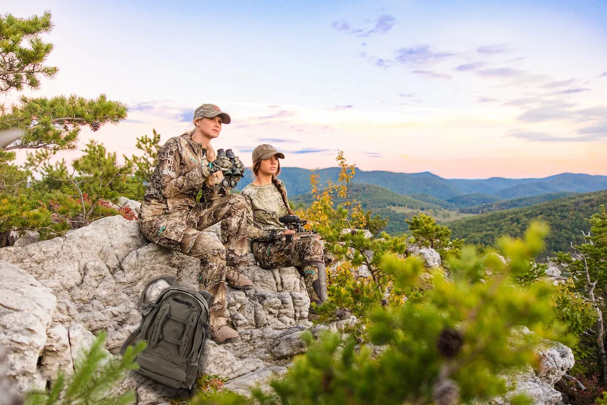 Female hunters sitting on rock ledge wearing DSG Outerwear