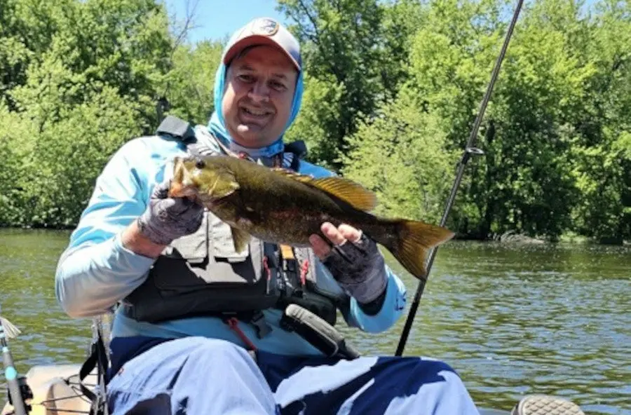 Angler in kayak holding fish caught with Shimano FX Spinning Combo