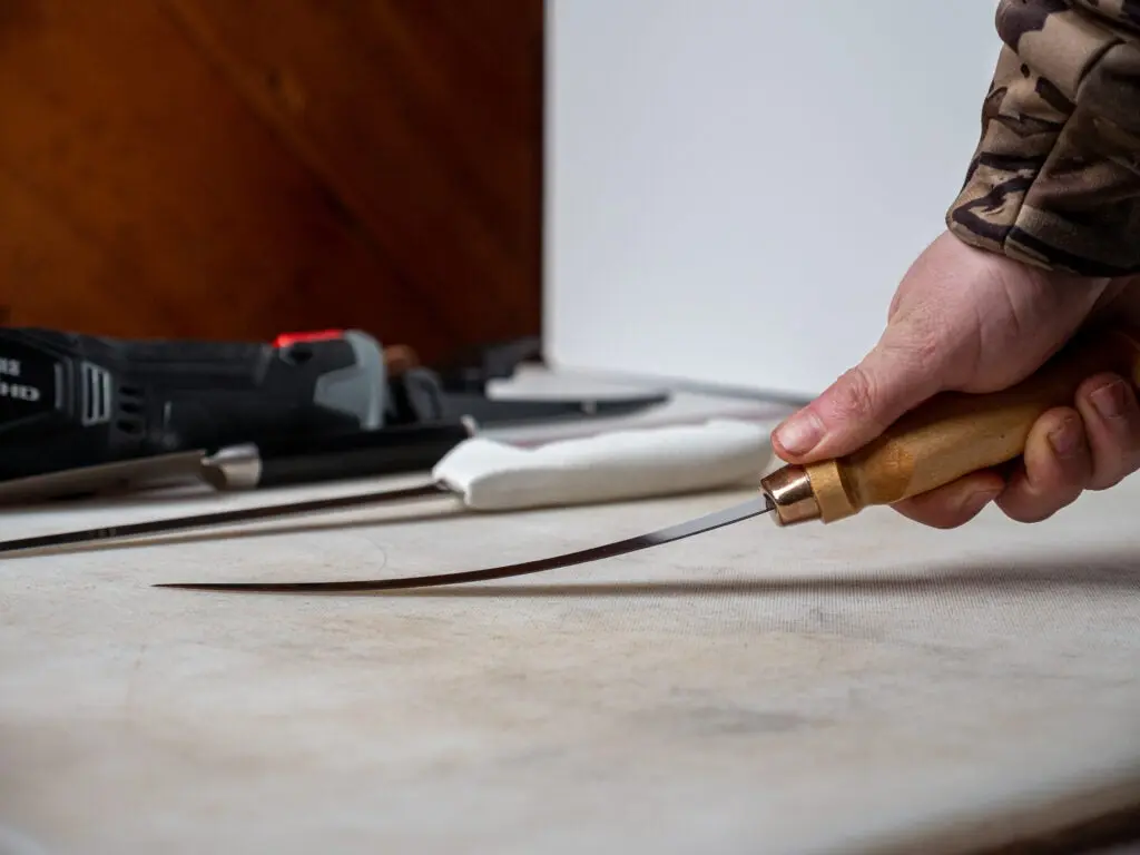 The Rapala Fish ân Fillet blade being flexed on a cutting board