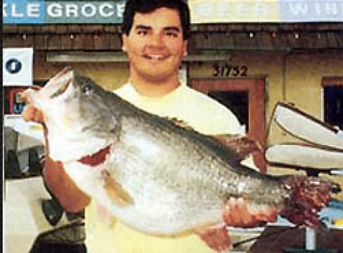 An angler poses with the California state record largemouth bass. 