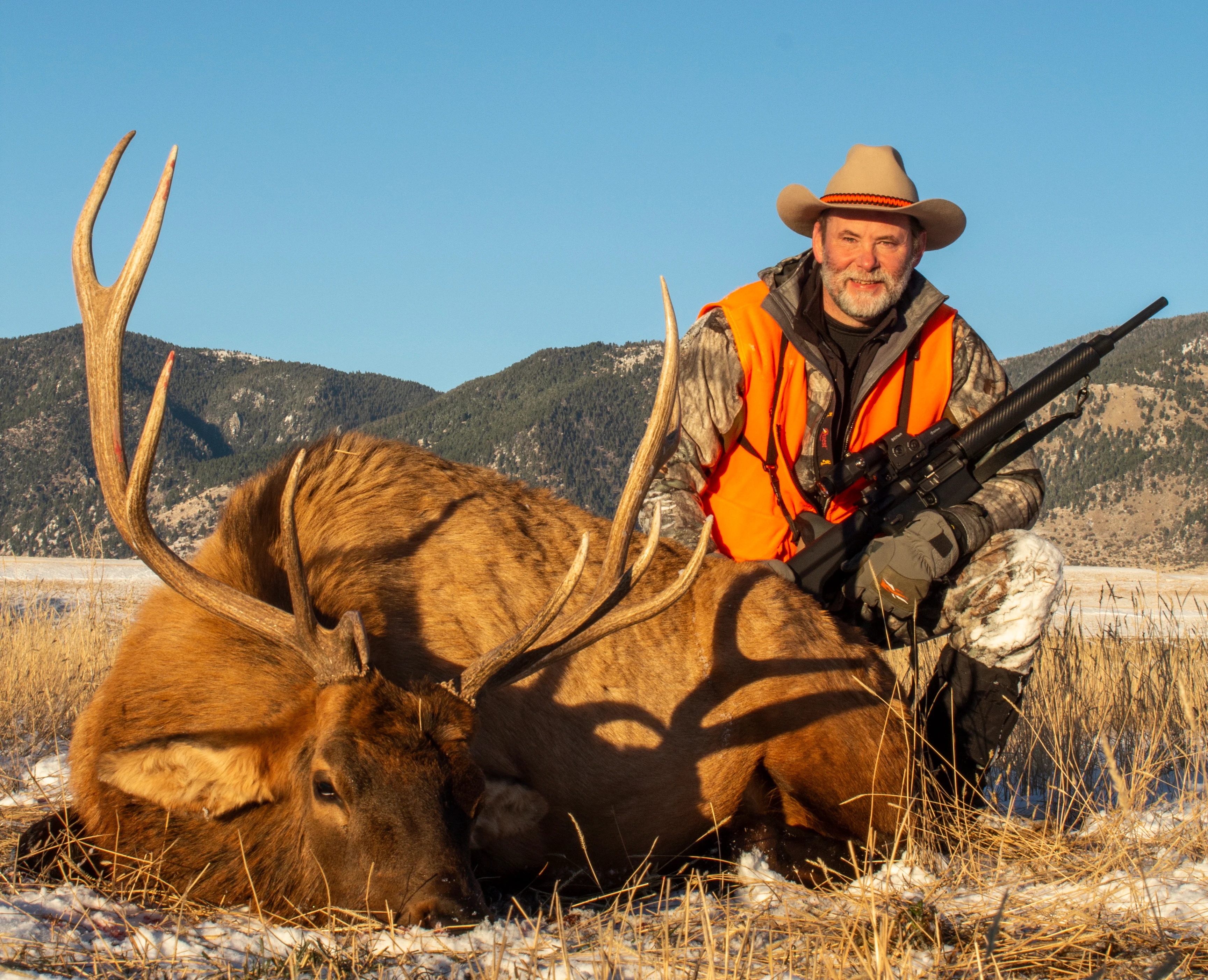 A hunter posing next to a bull elk he harvested.