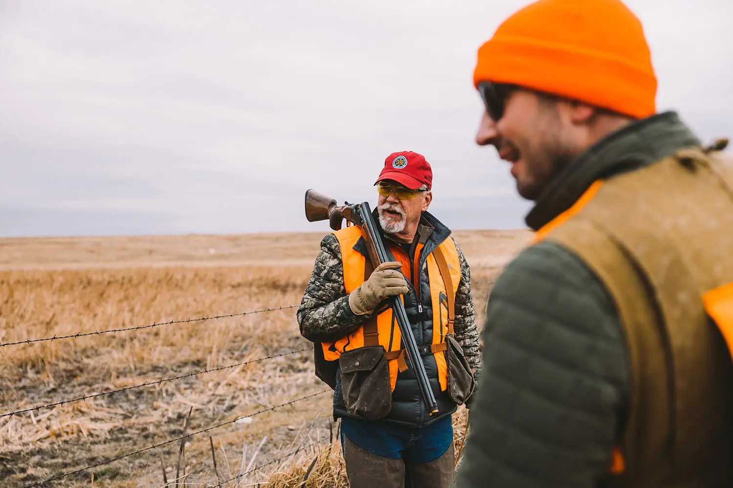 two bird hunters rest near barbed-wire fence